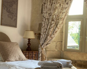 Chambre élégante "Amaury Le Roux" au Manoir de Kerledan, avec une décoration raffinée, des murs aux teintes douces, et un mobilier en bois ancien créant une atmosphère chaleureuse et intime.